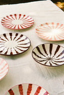 Set of ceramic plates with striped patterns on a white cloth.